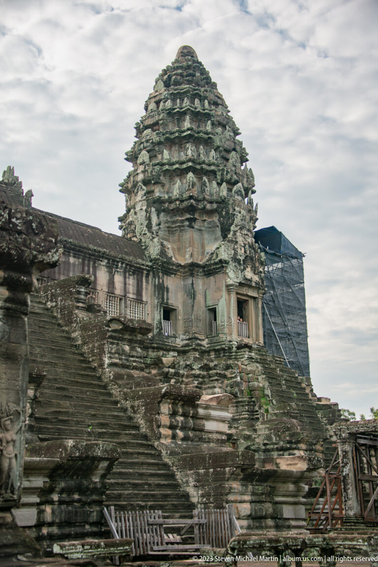 Weathered upper tower and gallery corner with scaffolding or protective structure at Angkor Wat.