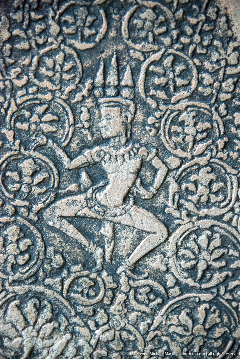 Dancing or flying figure surrounded by dense curling vegetal ornament at Angkor Wat.
