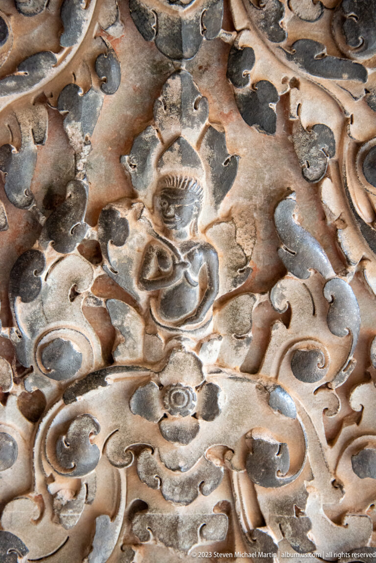 Close eroded face or mask surrounded by thick curling carved forms at Angkor Wat.