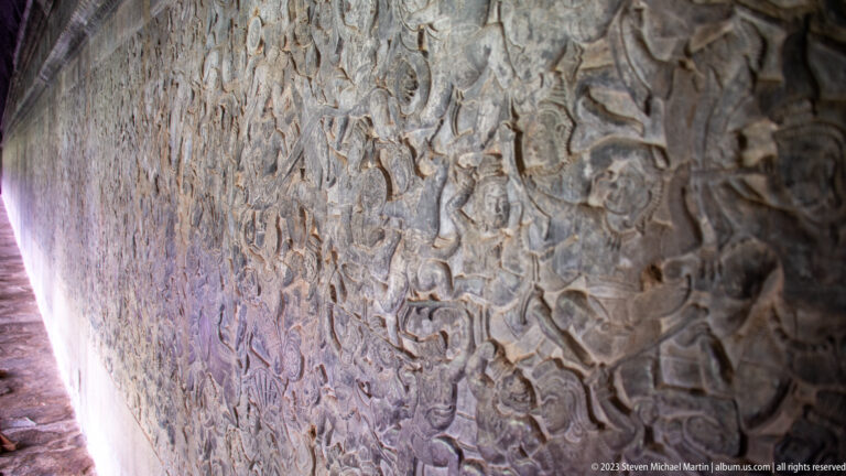 Wide wall relief crowded with numerous overlapping figures at Angkor Wat.