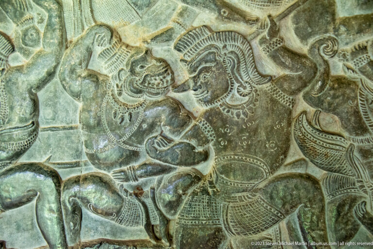 Close relief of a mounted or seated warrior-like figure amid scrolling forms at Angkor Wat.