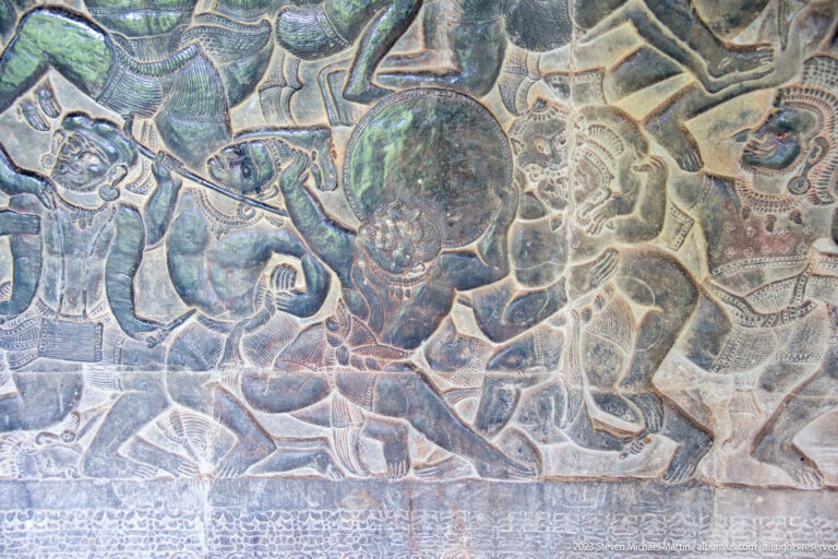 Central round shield or medallion surrounded by figures in a battle scene at Angkor Wat.
