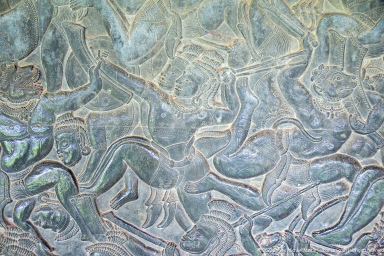 Dense battle relief with several figures, weapons, and overlapping bodies at Angkor Wat.