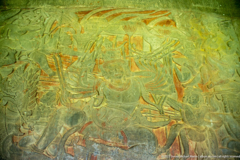 Wide colored processional or battle scene with standing figures and weapons at Angkor Wat.