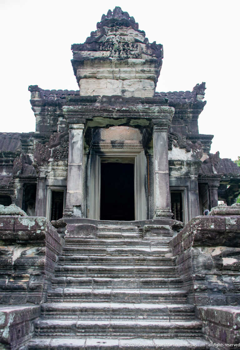 Weathered rectangular temple doorway reached by a short central stair at Angkor Wat.