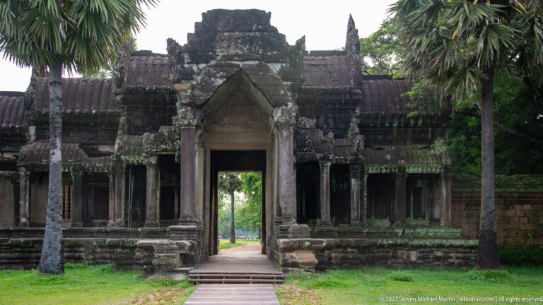 Frontal doorway opening through a gallery to bright greenery beyond at Angkor Wat.