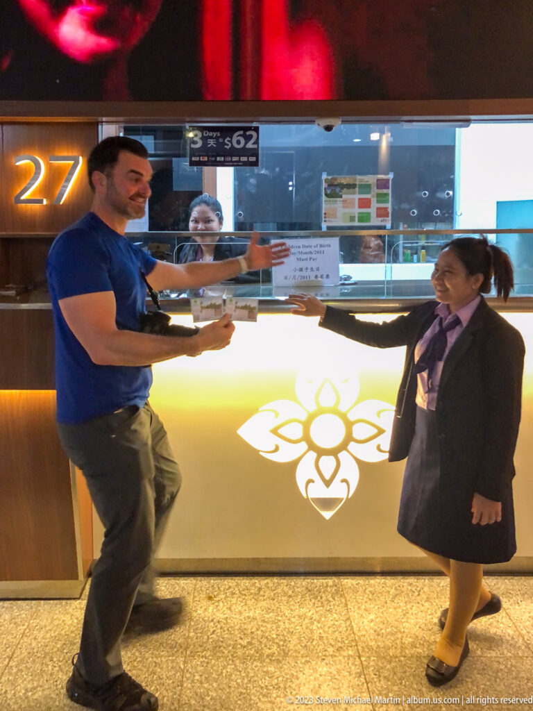 Man in blue playfully posing with a female staff member at an indoor counter at Angkor Wat.