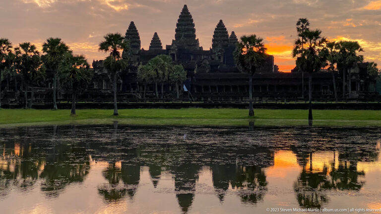 Angkor Wat silhouette and reflection against an orange sunset at Angkor Wat.