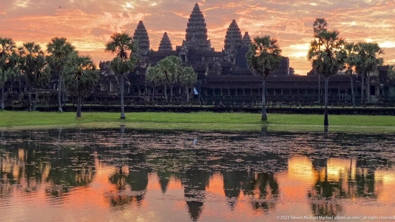 Angkor Wat towers and glowing orange sky reflected in the pool at sunset at Angkor Wat.