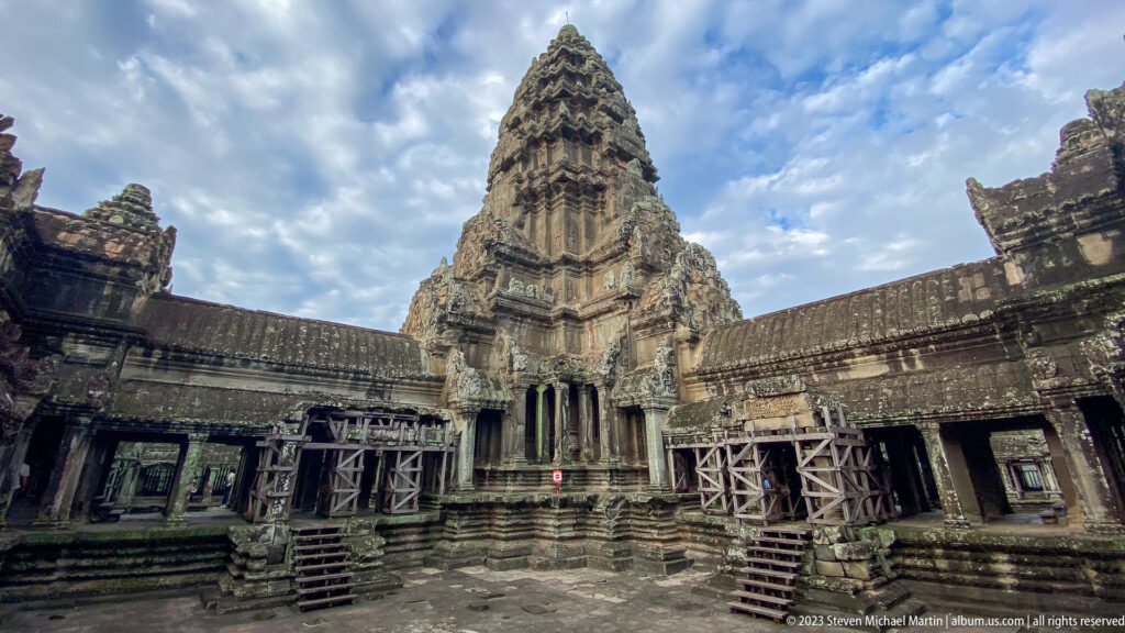 Interior courtyard with a tall lotus-bud tower and temporary wooden access stairs at Angkor Wat.