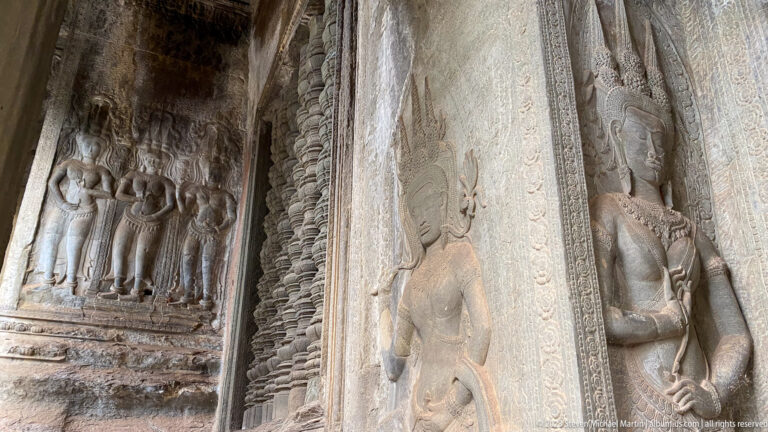Close wall panel showing devatas beside deeply carved vertical borders at Angkor Wat.