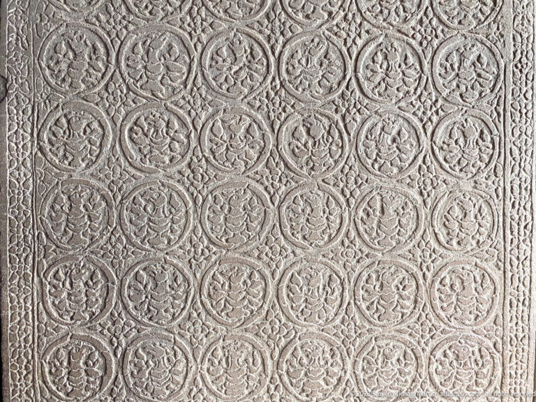 Large decorative wall panel filled with repeating circular floral medallions at Angkor Wat.