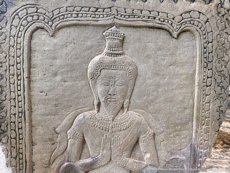 Single standing crowned figure carved in a bordered sandstone panel at Angkor Wat.