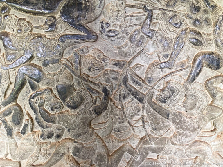 Dense battle relief with overlapping human and animal figures at Angkor Wat.