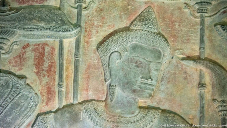 Close painted or naturally colored profile of a crowned Khmer figure on a relief wall at Angkor Wat.