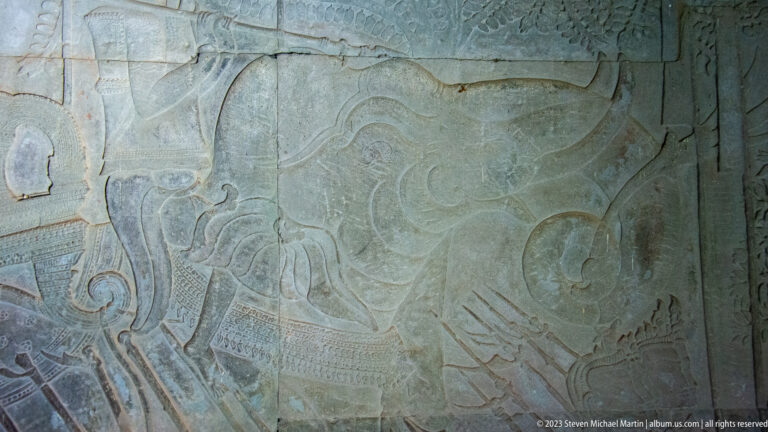 Faint broad bas-relief showing a large figure and curling decorative forms at Angkor Wat.