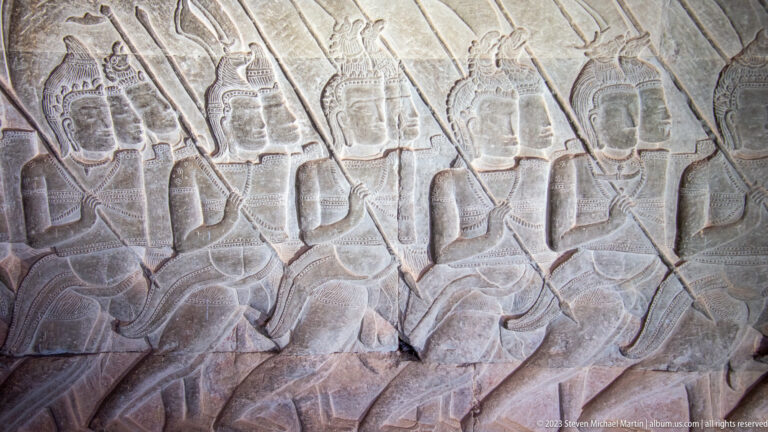 Close relief of several standing figures with long weapons or staffs at Angkor Wat.