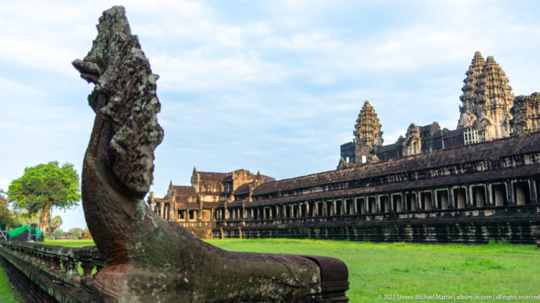 Profile of a stone naga or guardian balustrade with the long gallery behind at Angkor Wat.