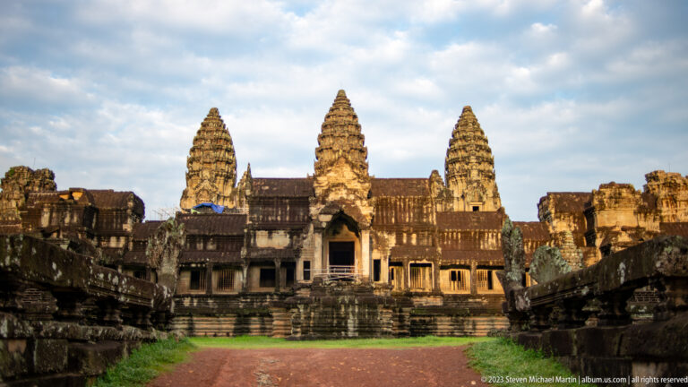 Closer frontal view of three towers and central western entrance in warm sunlight at Angkor Wat.