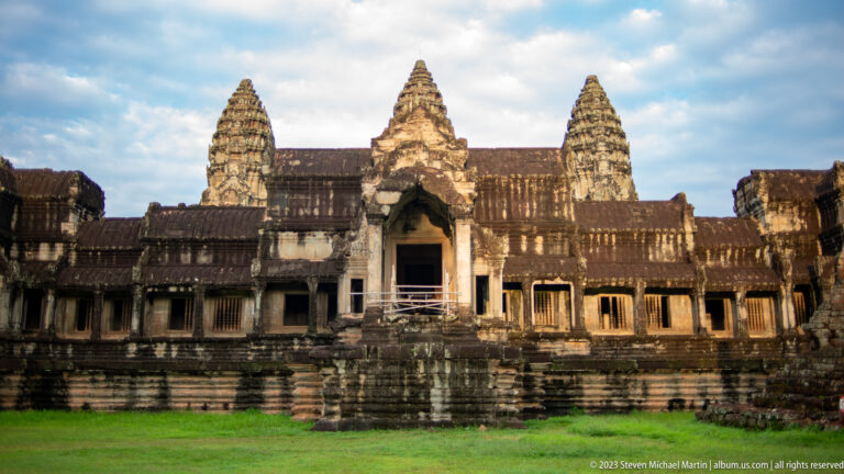 Central western entrance with three towers rising behind and grass in foreground at Angkor Wat.