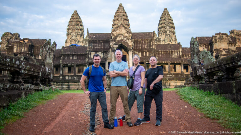 Four visitors posing on the central approach with Angkor Wat’s towers behind at Angkor Wat.