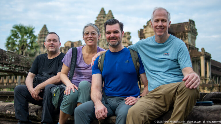 Closer seated group portrait of four visitors on the steps at Angkor Wat.