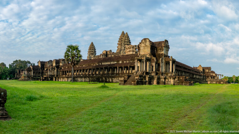 Very wide lawn view of the gallery corner and three towers at Angkor Wat.
