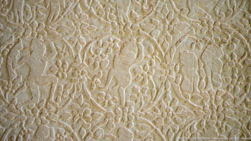 Flat sandstone panel covered with repeating small floral or circular motifs at Angkor Wat.