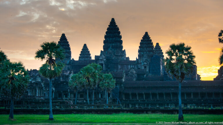 Closer blue-hour view of Angkor Wat towers rising above palms and the outer gallery at Angkor Wat.