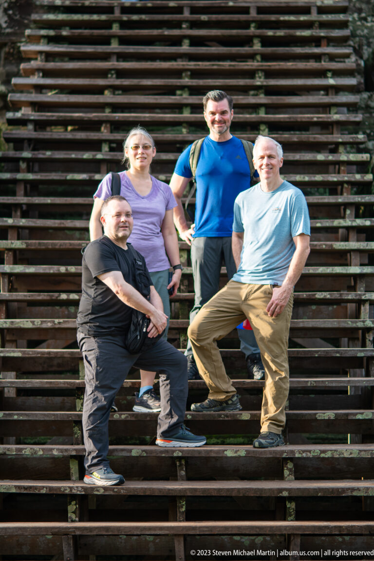 Four visitors posing on broad stone steps at Angkor Wat.