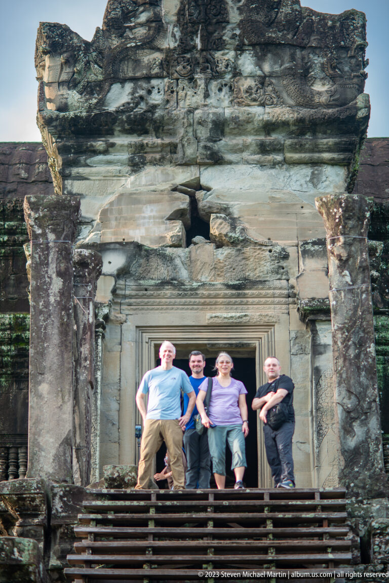 Four visitors standing beneath a carved doorway lintel at Angkor Wat.