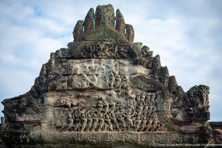 Large triangular pediment relief with dense small figures and a central sacred image at Angkor Wat.