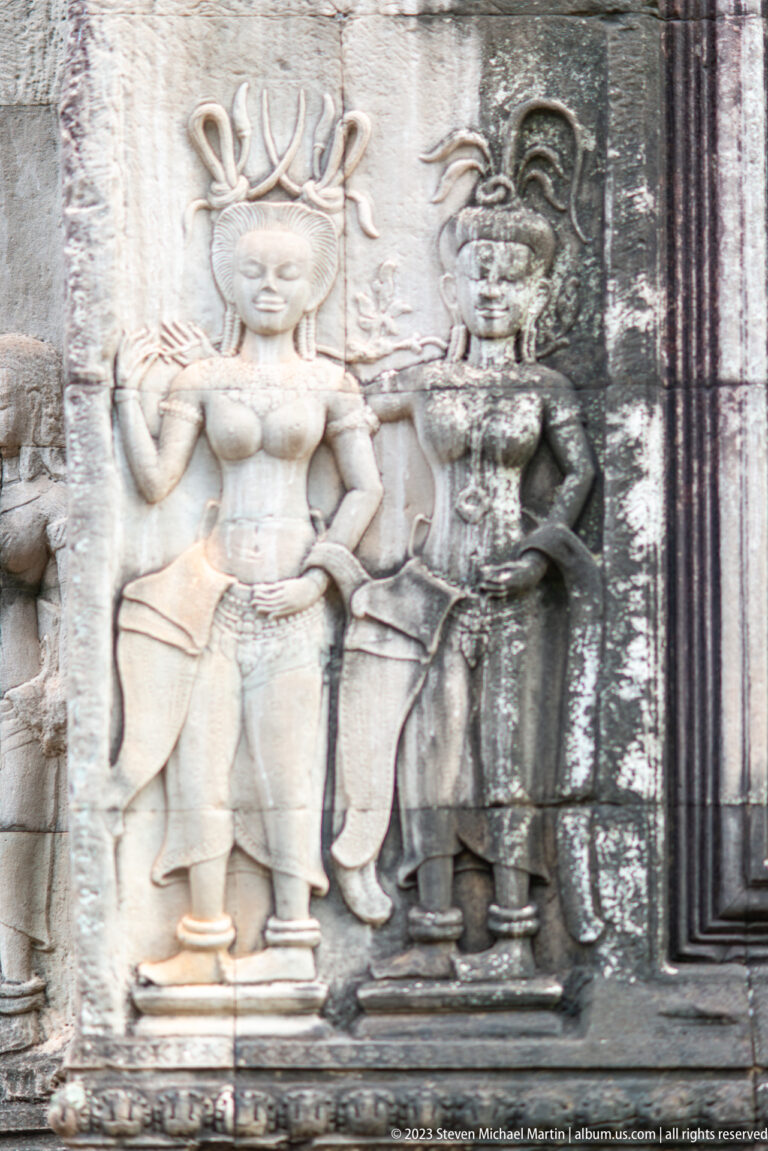 Close group of standing devatas carved beside a doorway at Angkor Wat.