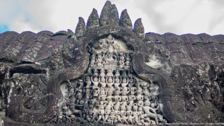 Triangular pediment densely filled with rows of small seated figures at Angkor Wat.