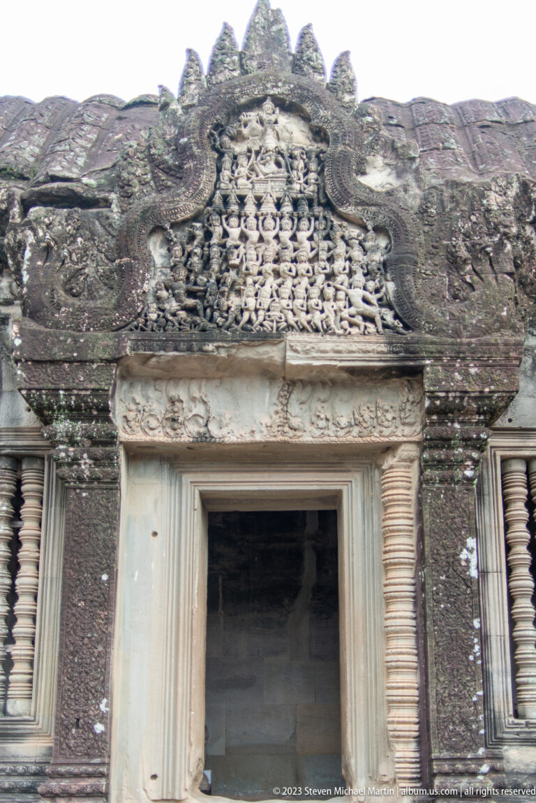 Carved figural panel and decorative lintel immediately above a doorway at Angkor Wat.