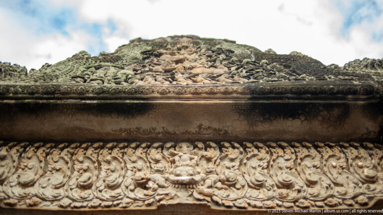 Rounded roof molding above a continuous floral scroll band at Angkor Wat.