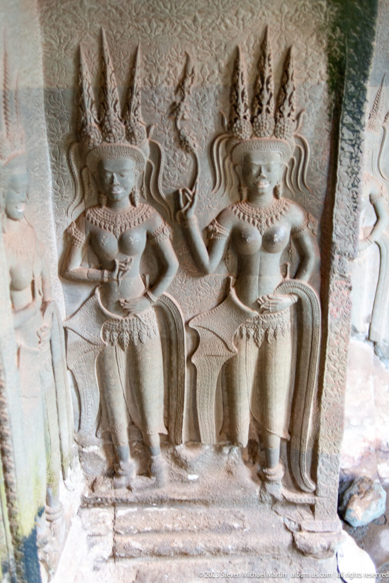 Pair of standing devatas shown from shoulders to knees at Angkor Wat.