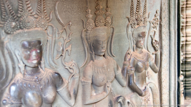Two crowned devatas with preserved faces and jewelry at Angkor Wat.