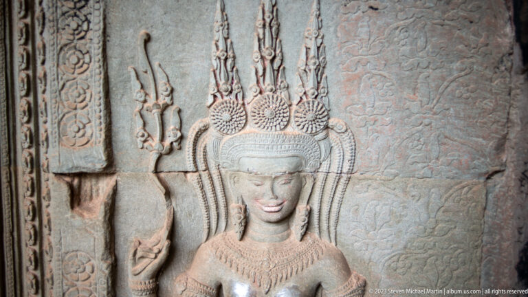 Close portrait-like devata with a very tall multi-tiered headdress at Angkor Wat.