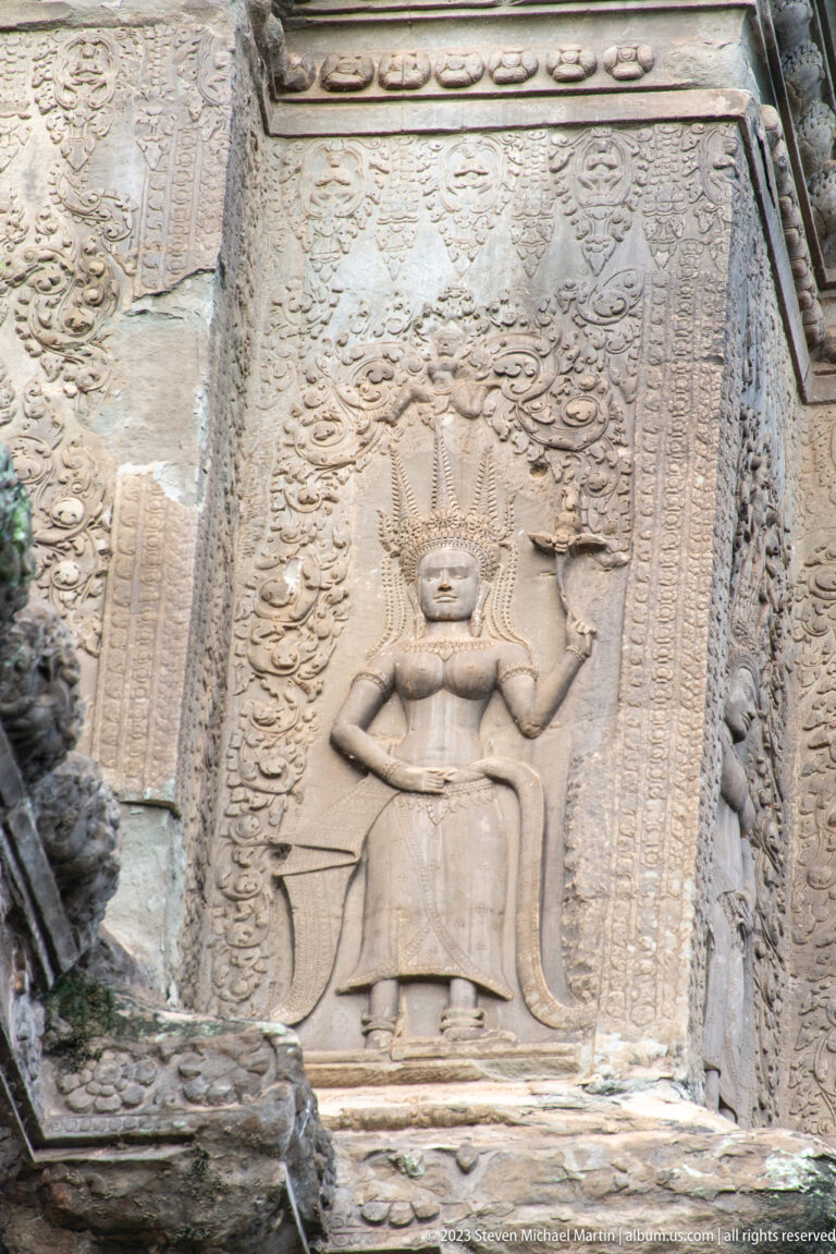 Single full-length standing devata in a narrow decorated panel at Angkor Wat.
