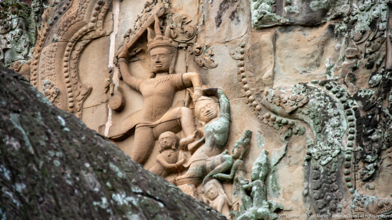 Large seated deity in a projecting exterior relief with smaller figures at Angkor Wat.