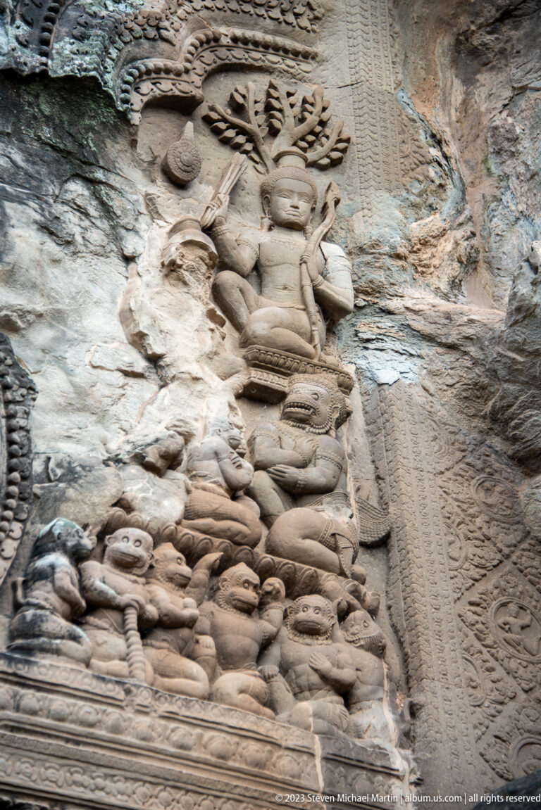 Large seated sacred figure above smaller kneeling or reclining figures at Angkor Wat.