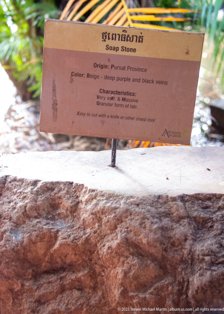 Stone sample beneath a sign describing purple and black veins and a very soft texture.