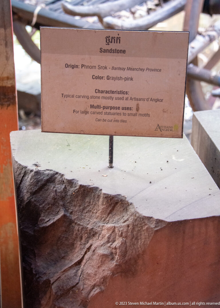 Grayish-pink stone block beneath a sign describing multipurpose carving use. inside the Artisans Angkor workshop in Siem Reap.