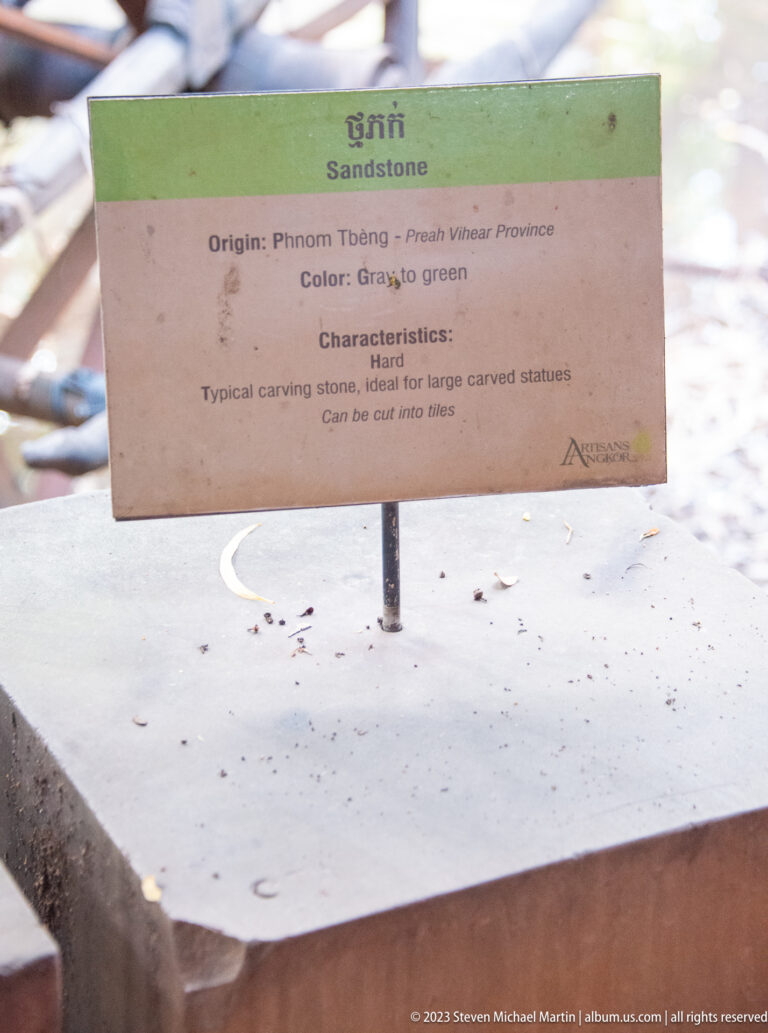 Gray-green stone block beneath a sign describing hard material for large carved statues.