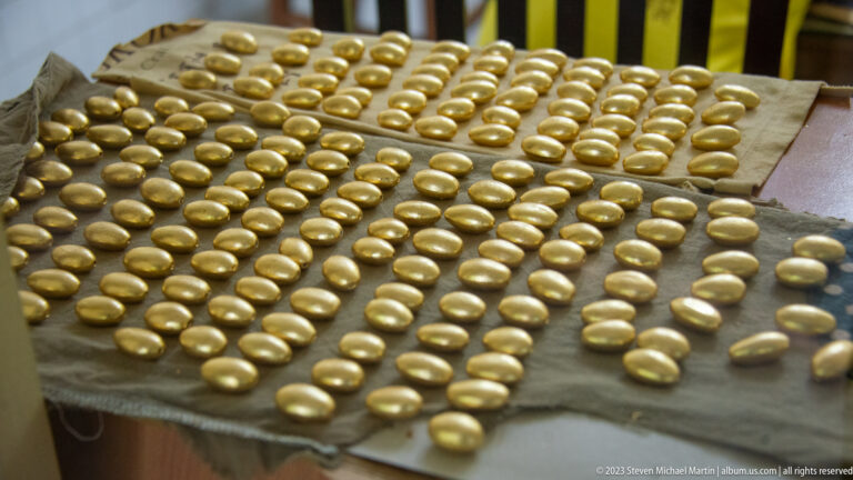 Close-up of many smooth gold-colored oval components arranged in rows. inside the Artisans Angkor workshop in Siem Reap.