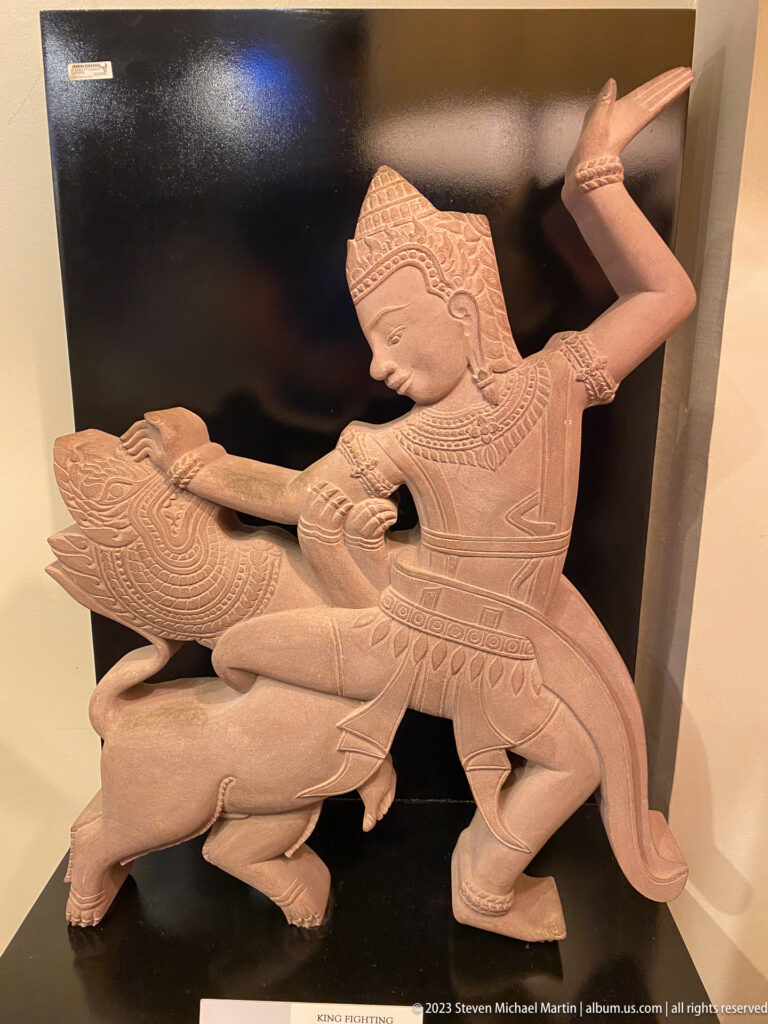 Finished pale stone sculpture of a kneeling woman holding a carved bird-like creature.
