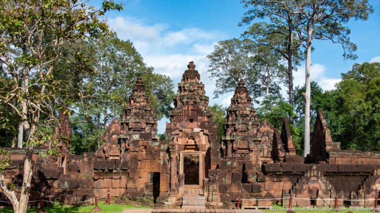 Frontal axial view through Banteay Srei's eastern entrance toward the central sanctuary tower, flanked by two smaller towers.