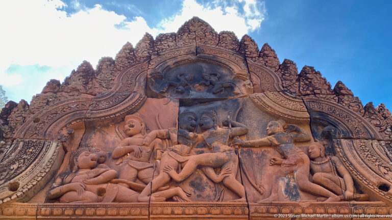Carved Banteay Srei pediment showing a dramatic mythological scene with a dominant central figure and surrounding figures.