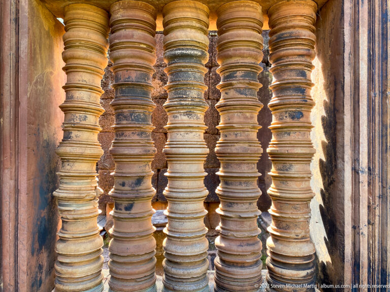 Close view of ringed sandstone window balusters lit by warm side light at Banteay Srei.